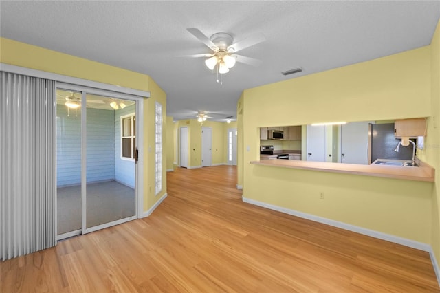 unfurnished room featuring sink, ceiling fan, a textured ceiling, and light wood-type flooring