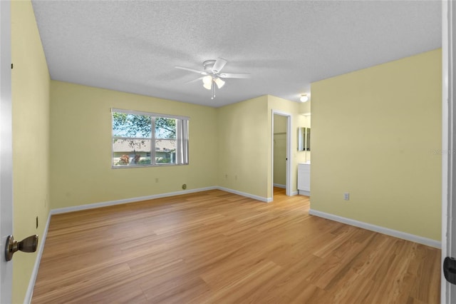 unfurnished room featuring ceiling fan, light hardwood / wood-style flooring, and a textured ceiling