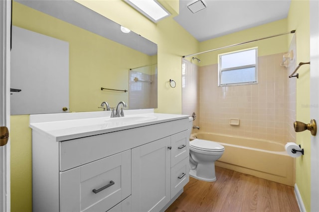 full bathroom with tiled shower / bath, vanity, toilet, and hardwood / wood-style floors