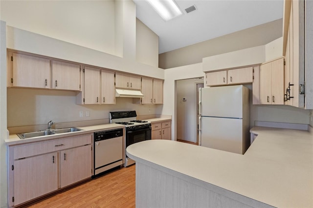 kitchen featuring white appliances, light brown cabinetry, sink, and light hardwood / wood-style flooring