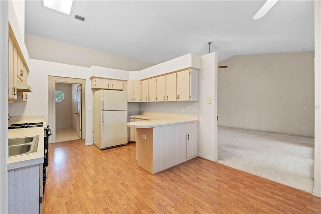 kitchen featuring vaulted ceiling, range with gas cooktop, white fridge, kitchen peninsula, and light wood-type flooring