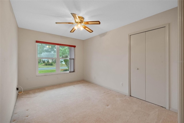 unfurnished bedroom with light colored carpet, a closet, and ceiling fan