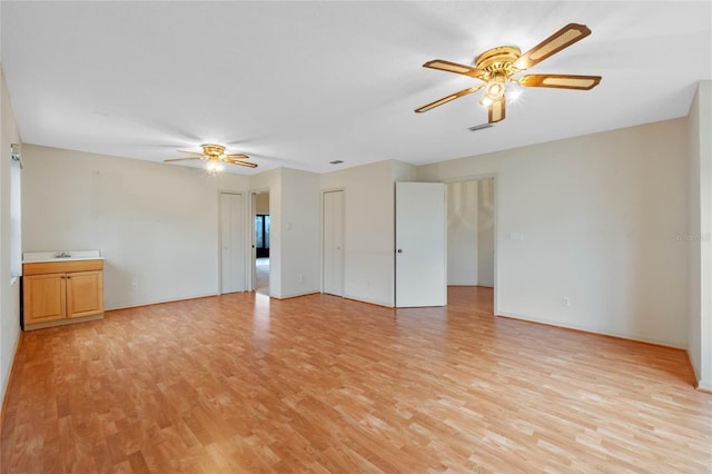 unfurnished room with sink, ceiling fan, and light wood-type flooring