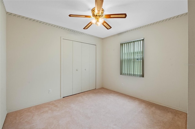 unfurnished bedroom with ceiling fan, light colored carpet, and a closet