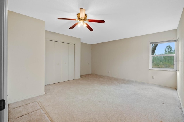 unfurnished bedroom with light colored carpet, ceiling fan, and a closet