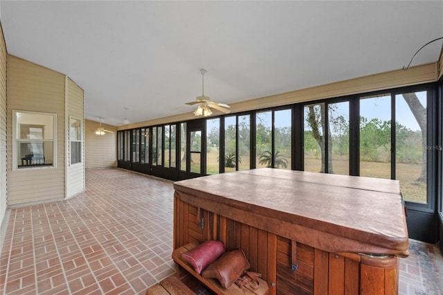 unfurnished sunroom featuring ceiling fan and a jacuzzi