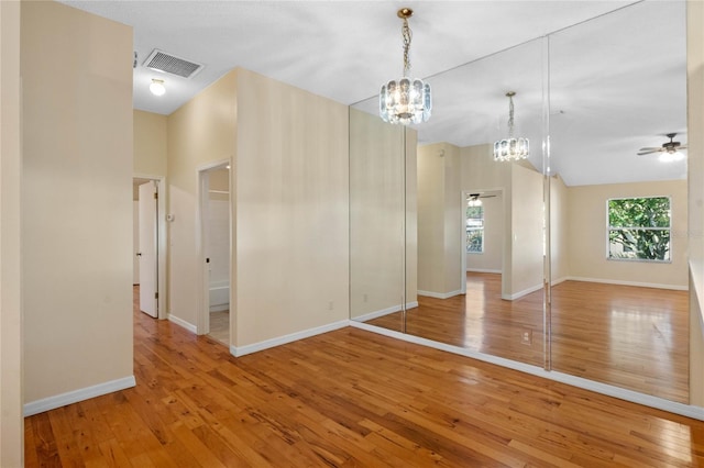 unfurnished room featuring lofted ceiling, hardwood / wood-style flooring, and a chandelier