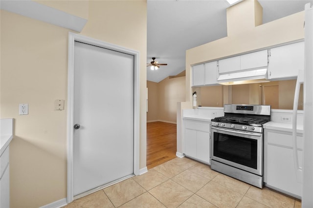 kitchen with vaulted ceiling, white cabinets, light tile patterned floors, ceiling fan, and stainless steel gas range