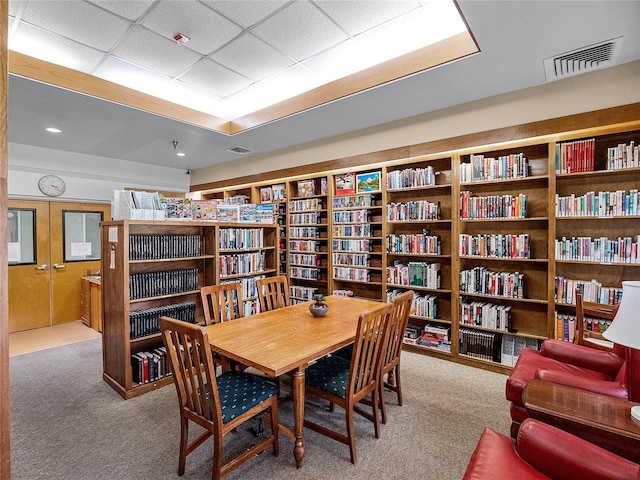 interior space with a paneled ceiling and light colored carpet