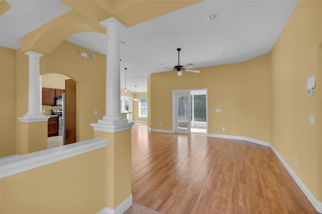 unfurnished living room featuring ornate columns, ceiling fan, and light wood-type flooring