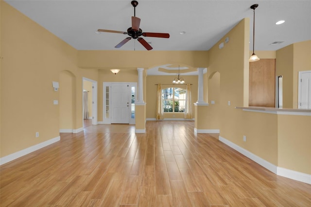 unfurnished living room featuring ceiling fan with notable chandelier, decorative columns, and light hardwood / wood-style floors