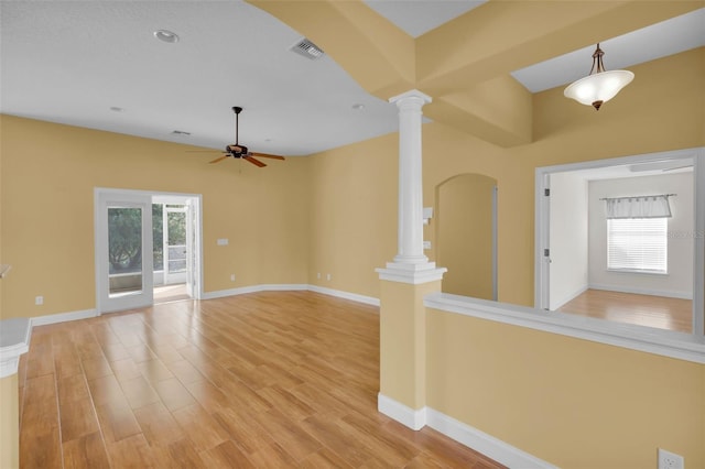 unfurnished living room featuring decorative columns, ceiling fan, and light wood-type flooring