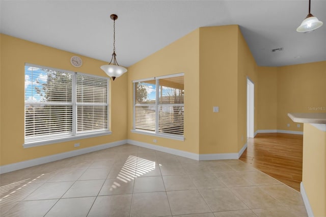 unfurnished dining area featuring light tile patterned flooring and vaulted ceiling