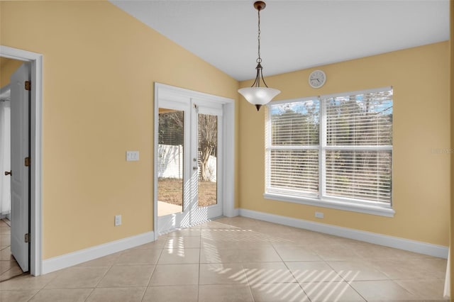 unfurnished dining area with vaulted ceiling and light tile patterned floors