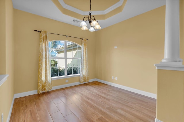 unfurnished dining area with ornamental molding, a tray ceiling, light hardwood / wood-style floors, and a notable chandelier