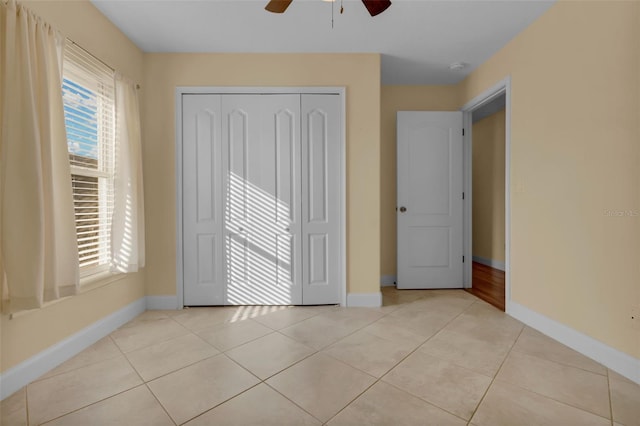 unfurnished bedroom with light tile patterned floors, a closet, and ceiling fan