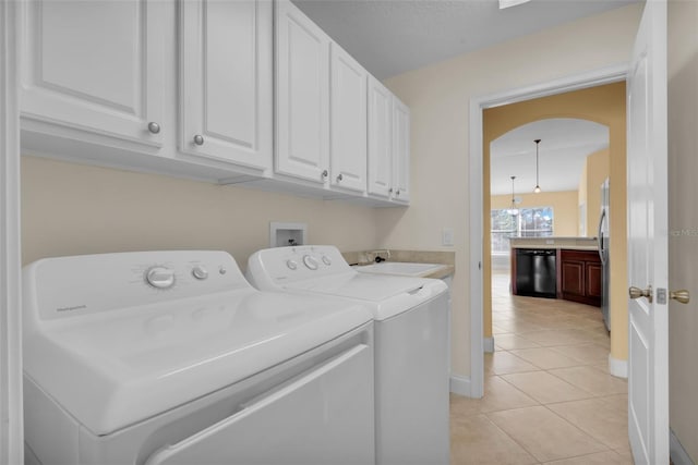 clothes washing area with separate washer and dryer, light tile patterned floors, sink, and cabinets