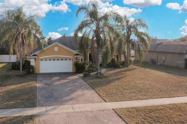 view of front of home with a garage, a front yard, and central air condition unit