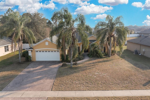 view of front of home with a garage, a front yard, and central air condition unit