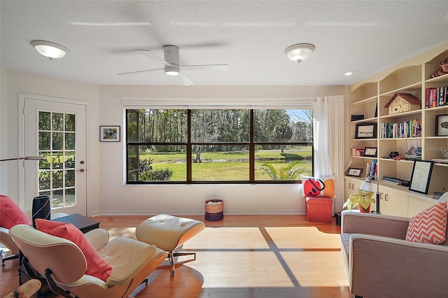 living area featuring ceiling fan, light hardwood / wood-style floors, and a textured ceiling