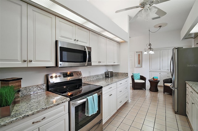 kitchen with appliances with stainless steel finishes, white cabinetry, hanging light fixtures, light tile patterned floors, and light stone counters