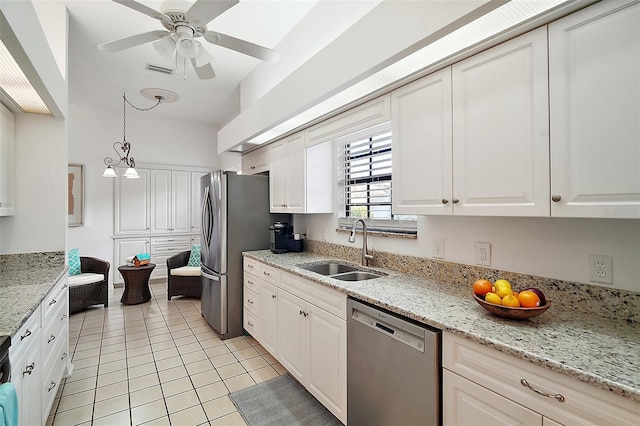 kitchen featuring sink, light tile patterned floors, appliances with stainless steel finishes, white cabinetry, and light stone counters