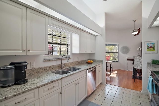 kitchen with light tile patterned flooring, sink, white cabinets, stainless steel appliances, and light stone countertops