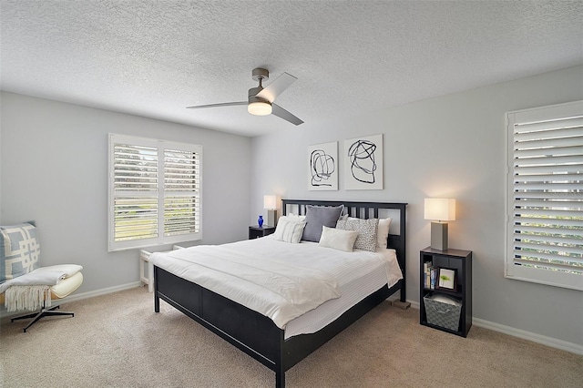 bedroom featuring ceiling fan, light colored carpet, and a textured ceiling