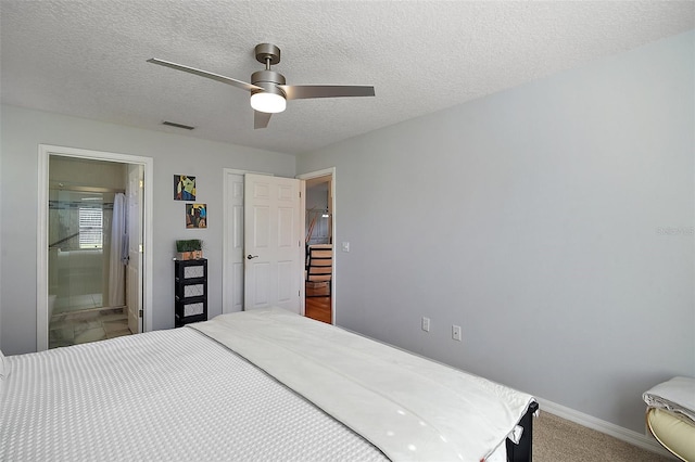 carpeted bedroom with ceiling fan, ensuite bathroom, and a textured ceiling