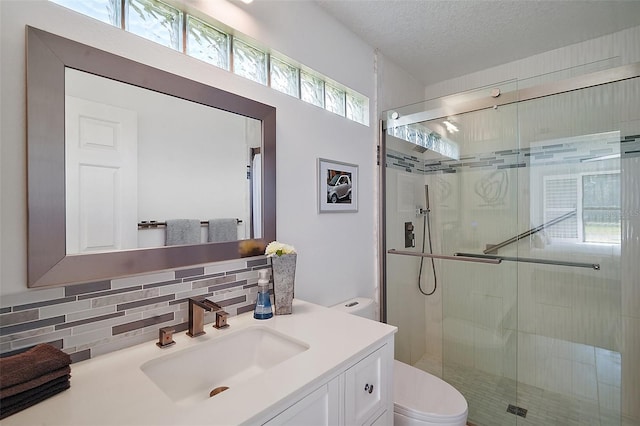 bathroom with backsplash, vanity, a textured ceiling, toilet, and walk in shower