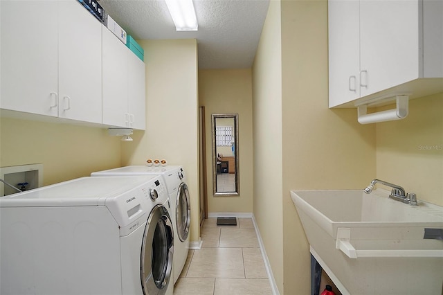 laundry room featuring light tile patterned flooring, sink, cabinets, washer and dryer, and a textured ceiling