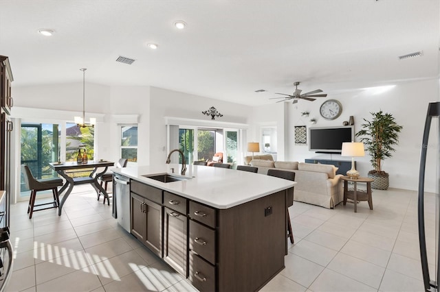 kitchen featuring light tile patterned flooring, an island with sink, sink, hanging light fixtures, and stainless steel dishwasher