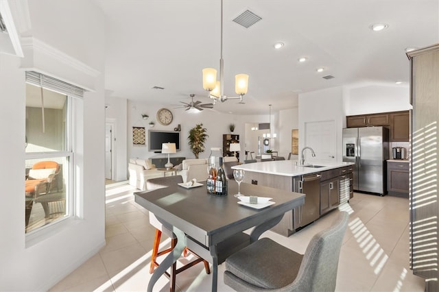 tiled dining room with sink and ceiling fan with notable chandelier