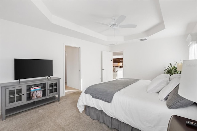 carpeted bedroom featuring a tray ceiling and ceiling fan