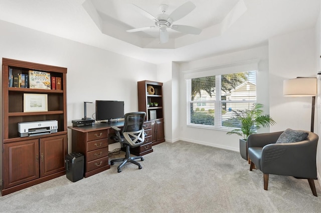 office featuring light carpet, a tray ceiling, and ceiling fan