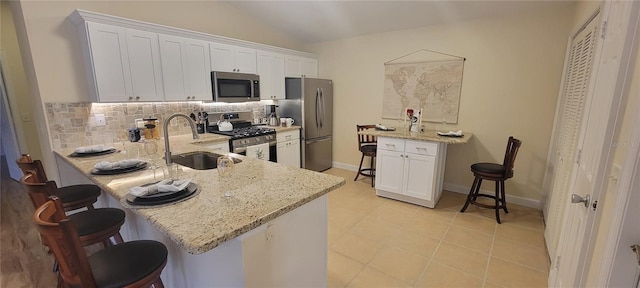 kitchen with sink, white cabinetry, light stone counters, kitchen peninsula, and stainless steel appliances