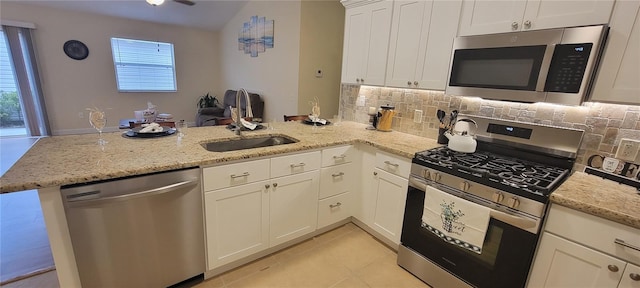 kitchen featuring a peninsula, appliances with stainless steel finishes, light stone counters, and white cabinets