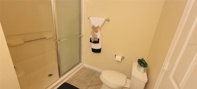 bathroom with a shower stall, toilet, and baseboards