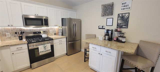 3621 Amelia Ave, The Villages, FL 32162 - kitchen with appliances with stainless steel finishes, a breakfast bar area, decorative backsplash, white cabinetry, and light stone countertops