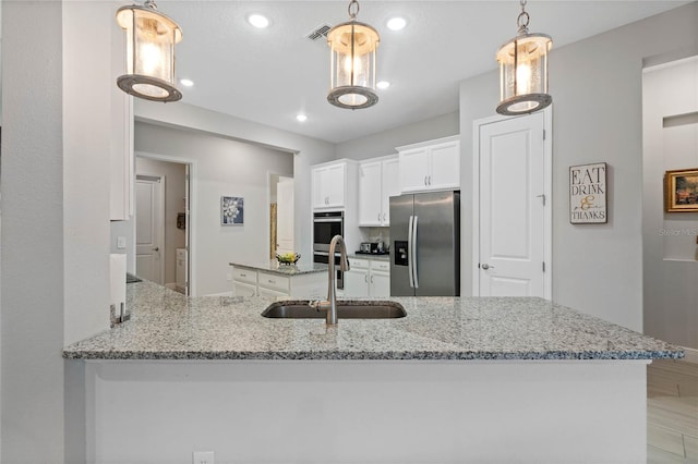 kitchen with sink, appliances with stainless steel finishes, white cabinetry, hanging light fixtures, and kitchen peninsula