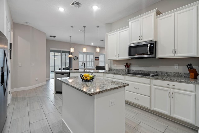 kitchen featuring appliances with stainless steel finishes, pendant lighting, white cabinets, a center island, and kitchen peninsula