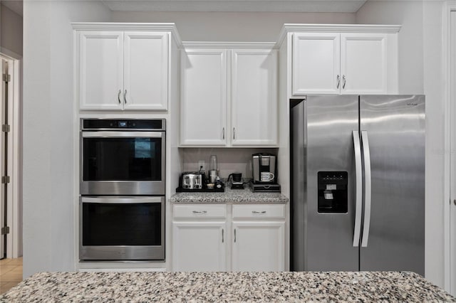 kitchen featuring light stone counters, appliances with stainless steel finishes, and white cabinets