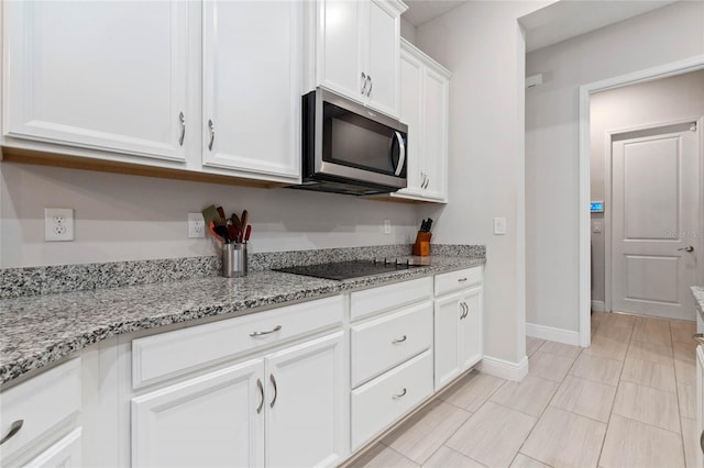 kitchen featuring white cabinetry, black electric stovetop, and light stone counters