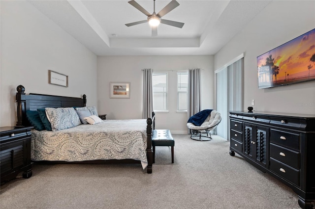 carpeted bedroom featuring ceiling fan and a raised ceiling