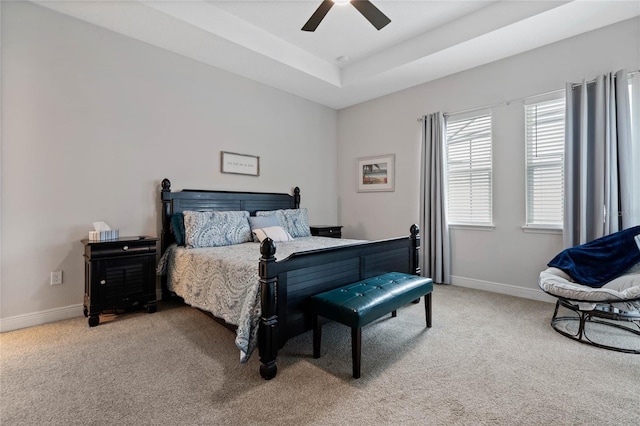 bedroom with a raised ceiling, carpet flooring, and ceiling fan