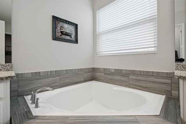 bathroom featuring vanity and a relaxing tiled tub