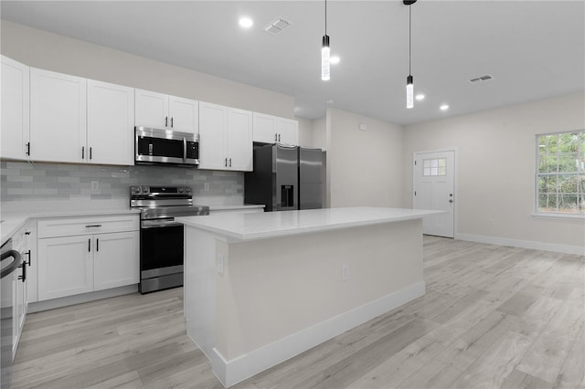 kitchen with a center island, hanging light fixtures, stainless steel appliances, decorative backsplash, and white cabinets