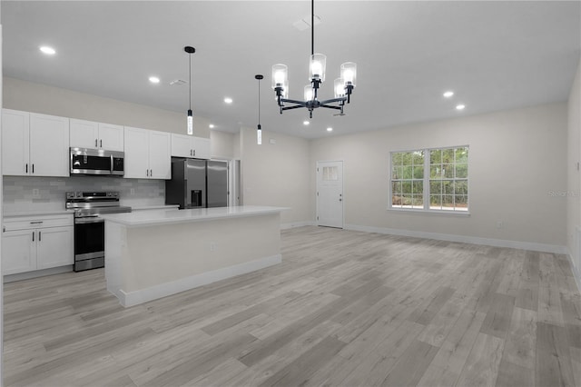 kitchen featuring a kitchen island, decorative light fixtures, white cabinetry, backsplash, and stainless steel appliances