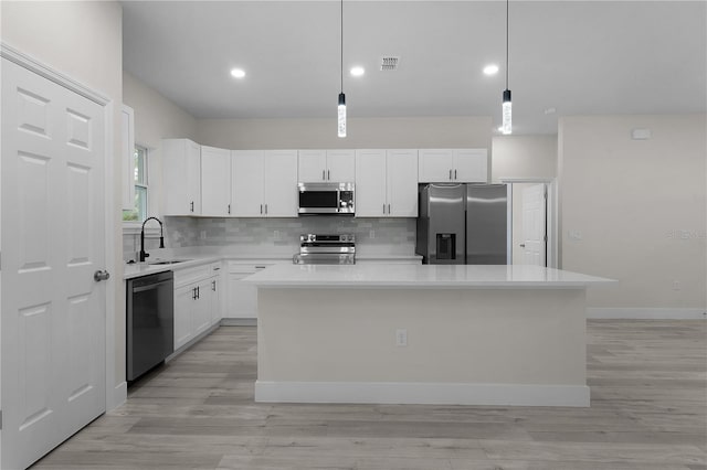 kitchen featuring sink, white cabinetry, hanging light fixtures, a kitchen island, and stainless steel appliances