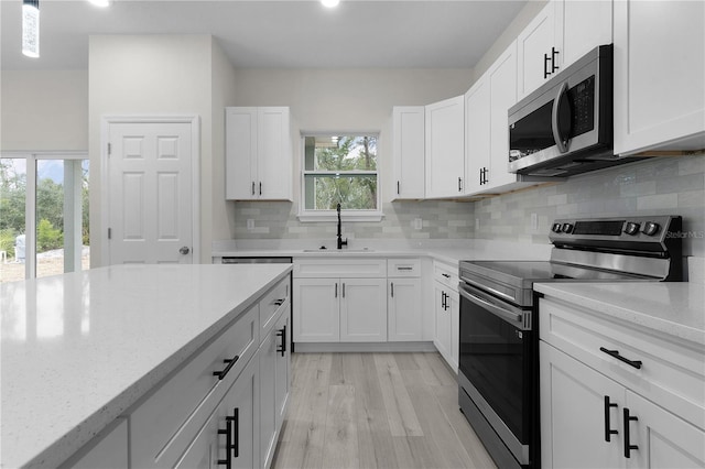 kitchen featuring appliances with stainless steel finishes, sink, backsplash, white cabinets, and light stone counters